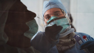 A technician takes a nasal swab for a new coronavirus detection test at a drive-thru testing facility in Abu Dhabi, United Arab Emirates.