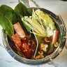 The duo base hot pot loaded with ingredients from the conveyor belt.