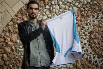 Palestinian Karam Qawasmi holds up the shirt he was wearing when he was shot.