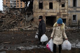 Residents carry bags of what they could salvage from their building, destroyed by an air strike.