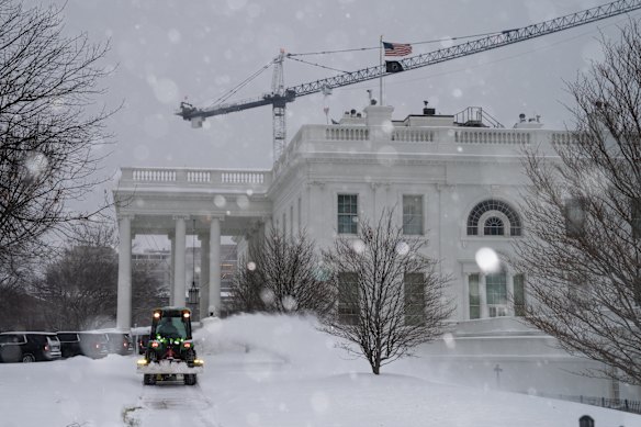 日曜日、ホワイトハウスの前の芝生から除雪する作業員。