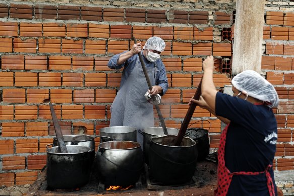 Walter Ferreira, left, and Laura Dure cook stew at a soup kitchen that feeds about 300 people daily in Luque, Paraguay. The UN World Food Program has warned more than 14 million people could go hungry in Latin America as the pandemic rages on.
