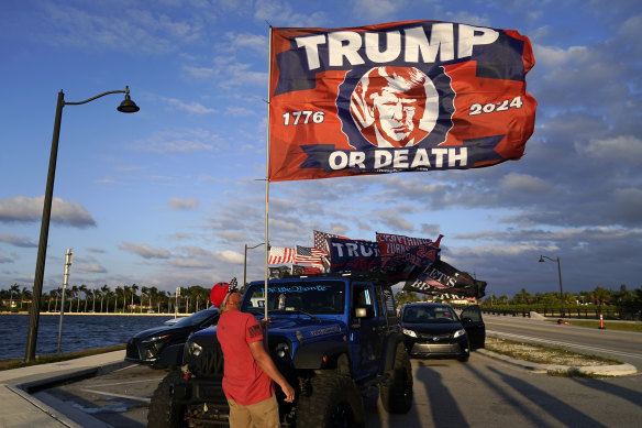 A supporter of former US president Donald Trump raises a flag outside of Trump’s Mar-a-Lago estate in Florida on Monday.