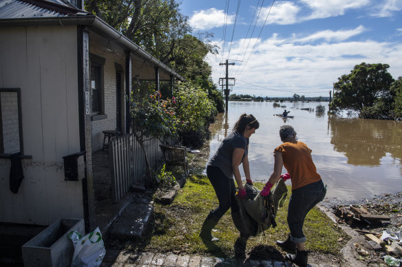 A friend helps Lisa Sullivan, right, carry a soggy pile outside. 