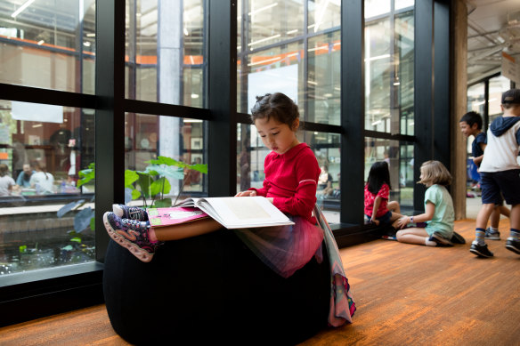 A student reads next to the glass fish pond. The school has thrown out the conventions of the so-called “industrial model” of teaching.