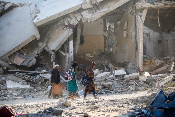People walk through destroyed buildings on Sunday after the IDF pulled out of Khan Younis.
