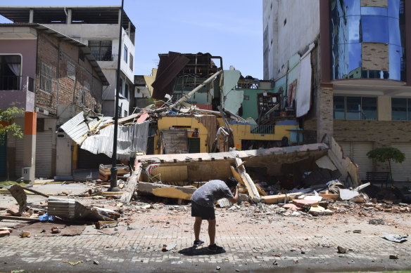 A man photographs a building that collapsed after an earthquake shook Machala, Ecuador on Saturday.