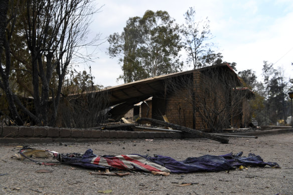 A charred Australian flag in front of a burnt-out home in Sarsfield, East Gippsland.