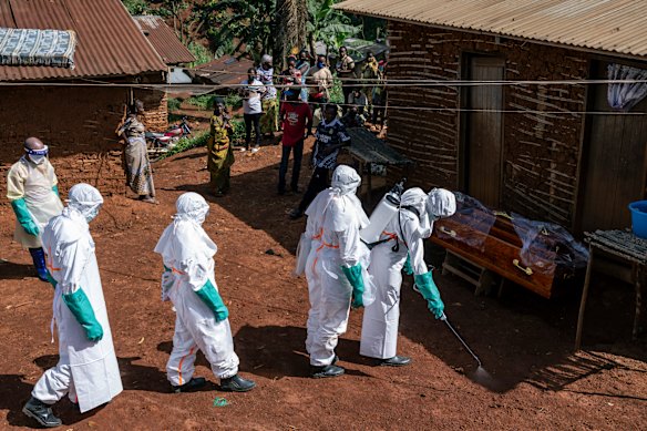 Health workers disinfect the entrance to a house before removing the body of a person whose suspected cause of death was Ebola, in Mongbwalu.