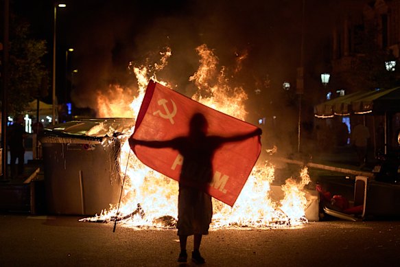 A protester holds a flag next to trash cans on fire during clashes with police following a demonstration over Spain’s housing crisis.