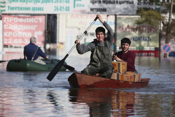 Two men ride a boat delivering food in Orenburg, Russia. Russian officials are scrambling to help homeowners displaced by the rising waters of the Ural River. 