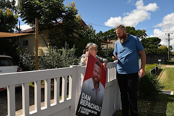 Dan Repacholi hands a corflute to constituent Liz Priestley to display in her front yard.