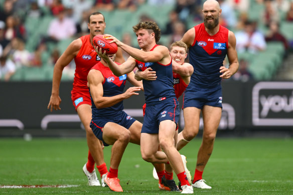 Harvey Langford of the Demons kicks whilst being tackled by Matt Rowell of the Suns.