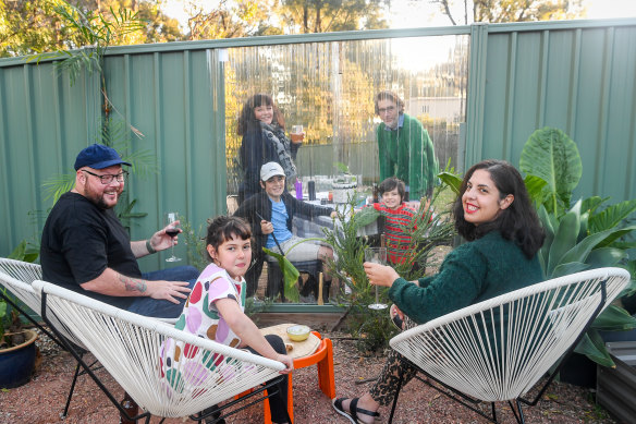 Laura Russo and Andrew Nicholson with their daughter Sigrid and, behind the transparent fence, their neighbours Leo Coyte and Kylie Banyard and sons Wes and Hal.