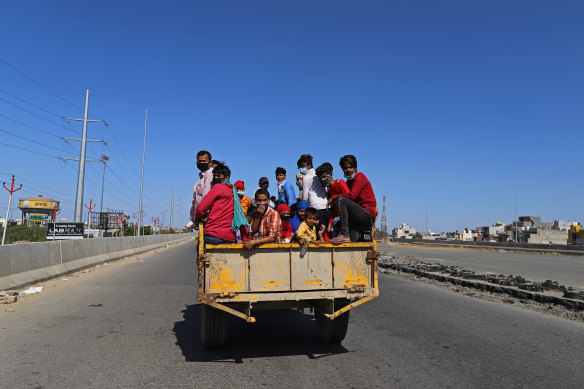 Migrant workers and their families sit in the back of a truck traveling along National Highway 24 on the outskirts of Delhi during the lockdown.