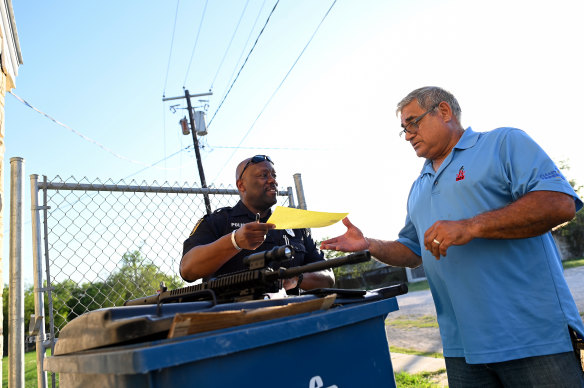 Richard Small, right, a retired high school teacher and a member of the National Rifle Association, receives paper work from Charlotte police officer Garry Rogers after handing over his AR-15.