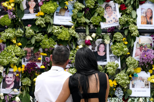 People stand near a makeshift memorial outside St Joseph Catholic Church near the Champlain Towers on Tuesday.