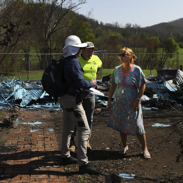 Kim McDonald talks with a NSW Public Works employee and a specialist in asbestos about the cleanup after her home was destroyed. 