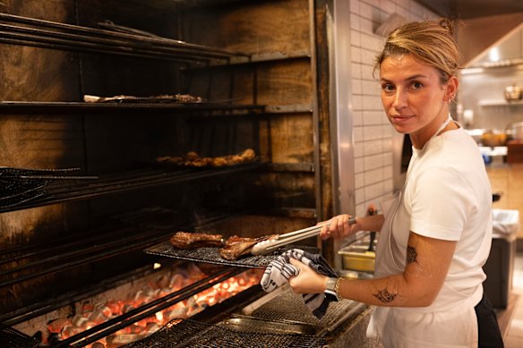 Ozge Kalvo turns lamb on the charcoal grill at Olympus Dining. 