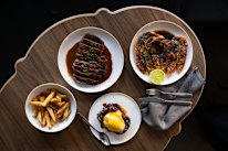 A spread of crab blini with hollandaise, chips, steak Diane and Skull Island prawns with black pepper butter (clockwise from left).