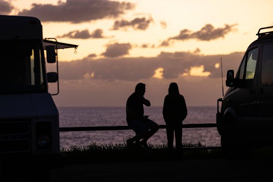 People gather by a coffee truck on the southern headland at Avalon Beach to watch the sunrise.