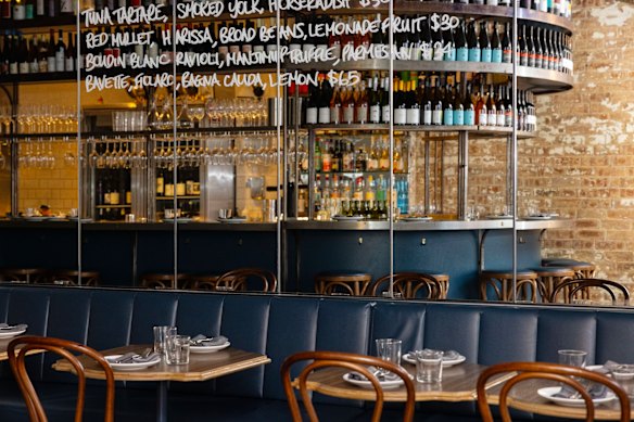 The industrial-styled dining room features ornately curved tables and long banquettes. 