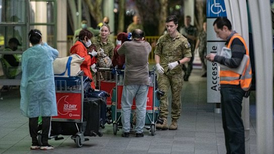Passengers are assisted at Sydney International Airport before being transported to a hotel for quarantine.
