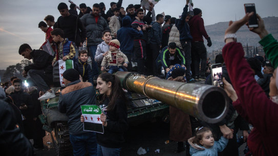 People sing and dance on top of a destroyed tank in Umayyad Square in Damascus, Syria, following the fall of the Assad regime.