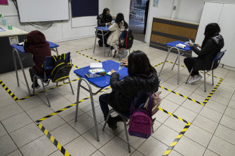 Tape marks each person's space to assure social distancing at a public school that has been repurposed as a daycare for minors with working parents in Santiago, Chile.
