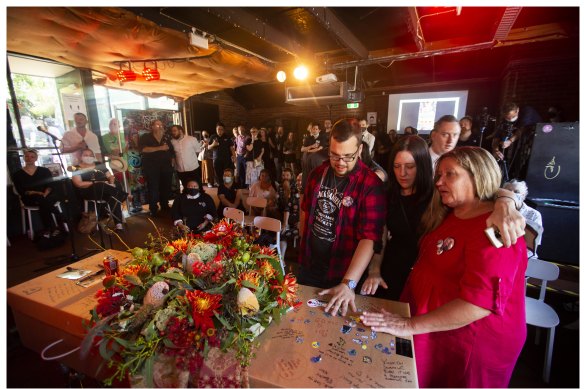 Steve Ellis’s mother Dianne, right, with friends and family, gather around his coffin at the Tote Hotel in Collingwood.