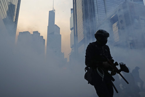 A police officer surrounded by tear gas.