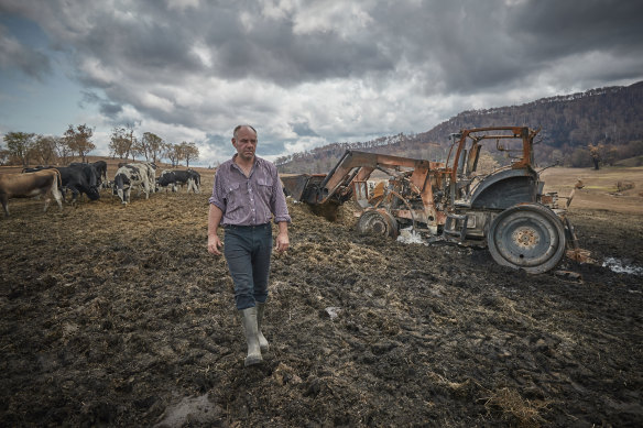 Farmer Farran Terlich walks past the burnt out remains of a tractor he used to fight the bushfire on his farm.