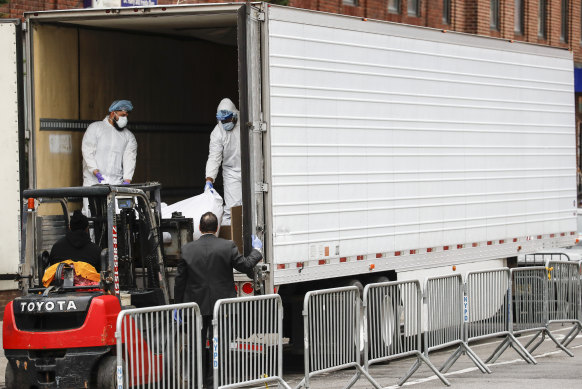A forklift loads a body onto a refrigerated truck, which is being used as a temporary morgue, in New York.