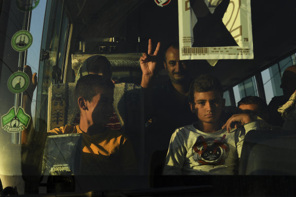 A man makes the peace sign from a minibus laden with refugees from Syria.