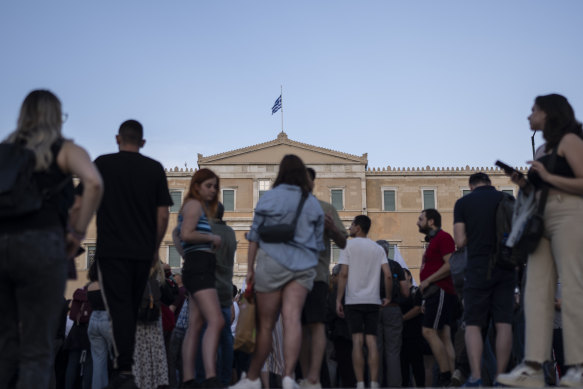The Greek flag waves at half-mast atop the Greek parliament.