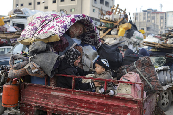 Displaced Palestinians gather with their belongings near a roadblock on Salah al-Din Street, as they wait.