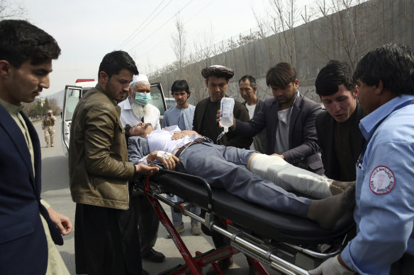 An injured man is carried away after gunman launched a deadly assault at a ceremony in Kabul.