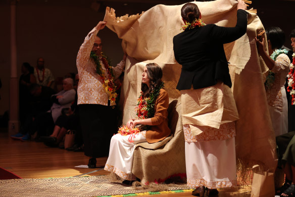 New Zealand Prime Minister Jacinda Ardern is covered by a mat of forgiveness during a service.