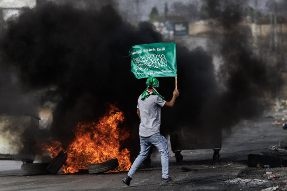 A Palestinian youth carries a Hamas flag amid clashes with Israeli soldiers in the West Bank on October 27.