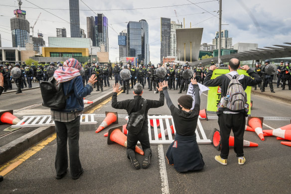 Protesters hold their hands in the air after a person was hit by a rubber bullet fired by police on Spencer Street Bridge on Wednesday.