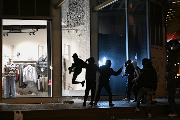 Rioters loot a shop in Paris during clashes on Sunday.