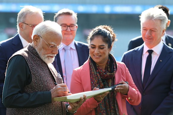 Indian PM Narendra Modi signs a bat for former Australian cricketer Lisa Sthalekhar, alongside Steve Waugh.