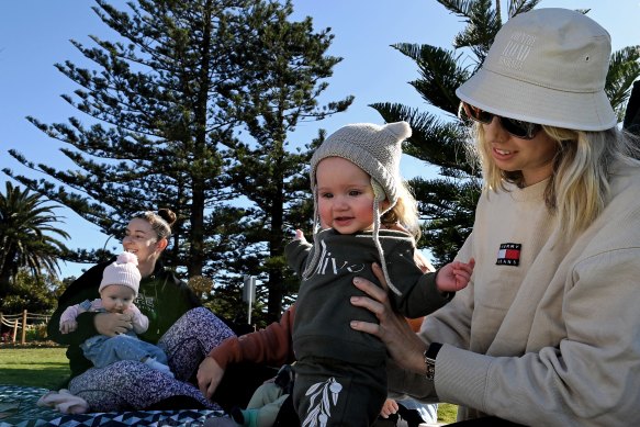 Belinda Melmoth (left) with her baby Ivy and Kelsie and baby Olive (right) with friends at a mothers group celebrating a birthday at North Wollongong beach.