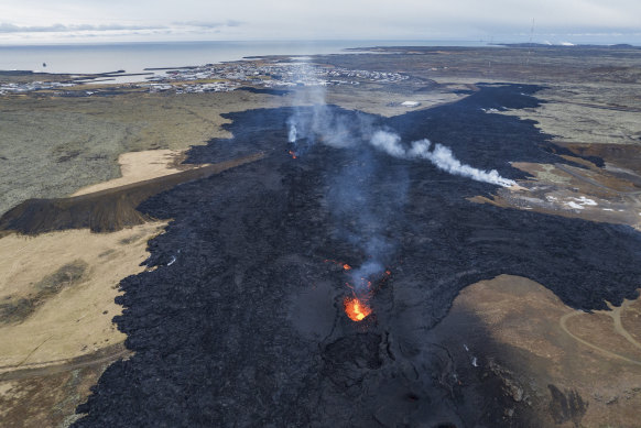 An aerial view of the lava field with the main active vent, the town of Grindavik is in the background.