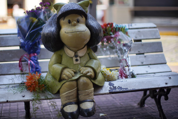 Flower tributes rest next to a statue of Mafalda in Buenos Aires after the death of Quino, her creator.