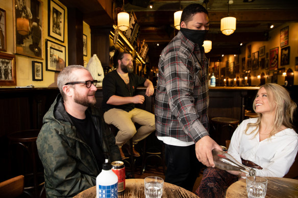 Pasan Wijesena wears a mask while serving customers at a Sydney bar.