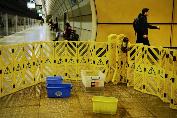 A commuter walks past buckets collecting dripping water at Epping metro station.