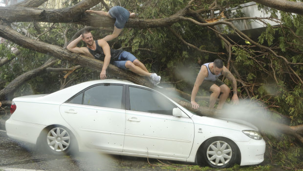 Tourists pose for selfies on top of a damaged car after Tropical Cyclone Marcus hit Darwin's CBD.