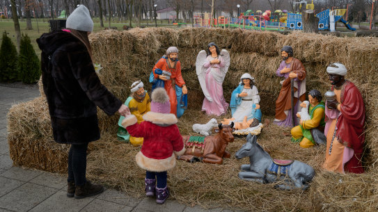 A mother and her child look at a Catholic Christian nativity scene in Pokrovsk, Ukraine.