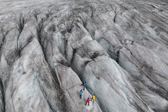 In this aerial view, a scientific team from the Swiss Federal Institute of Technology in Zurich (ETH) stands among crevasses on the Rhone Glacier during data collection near Gletsch, Switzerland.
